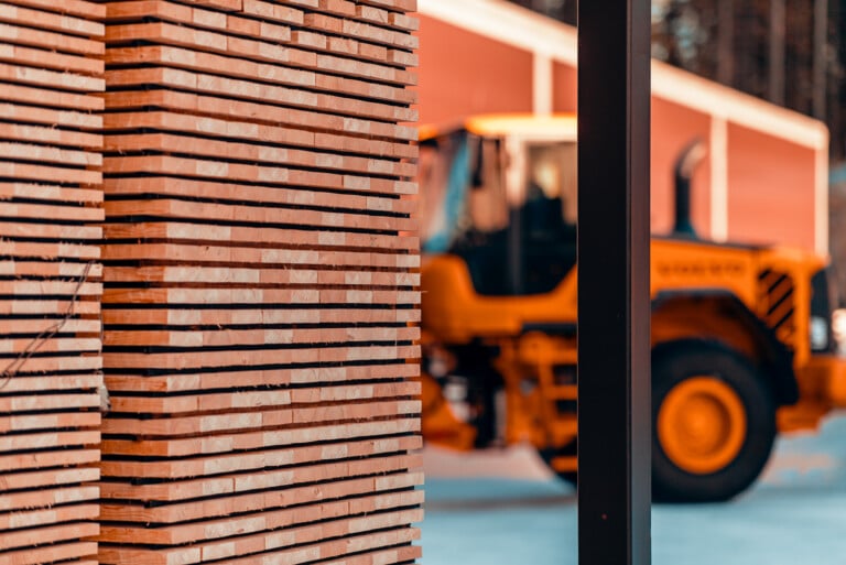 Stack of Thermowood with large Telehandler visible in background