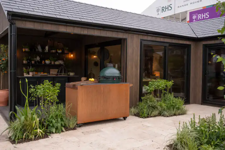 Open-sided outdoor kitchen area of the Malvern Garden Buildings Bespoke L-Shaped Garden Room at Chelsea Flower Show 2026