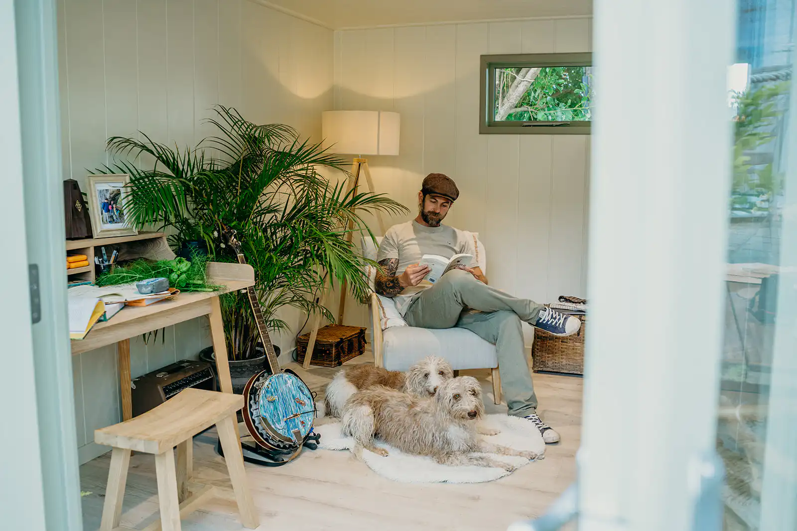Chef James Strawbridge sitting in a chair reading with his dog in his Studio Flat by Malvern Garden Buildings