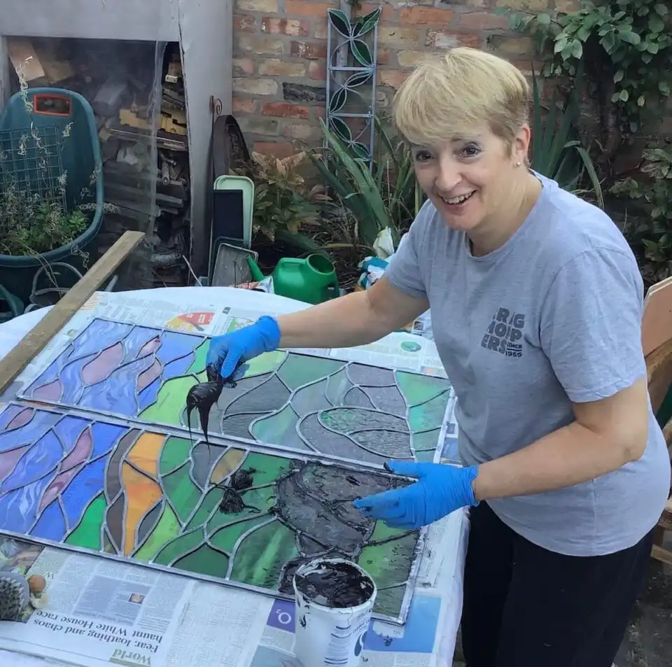 Sarah Davis cementing leaded stained glass panels in the garden