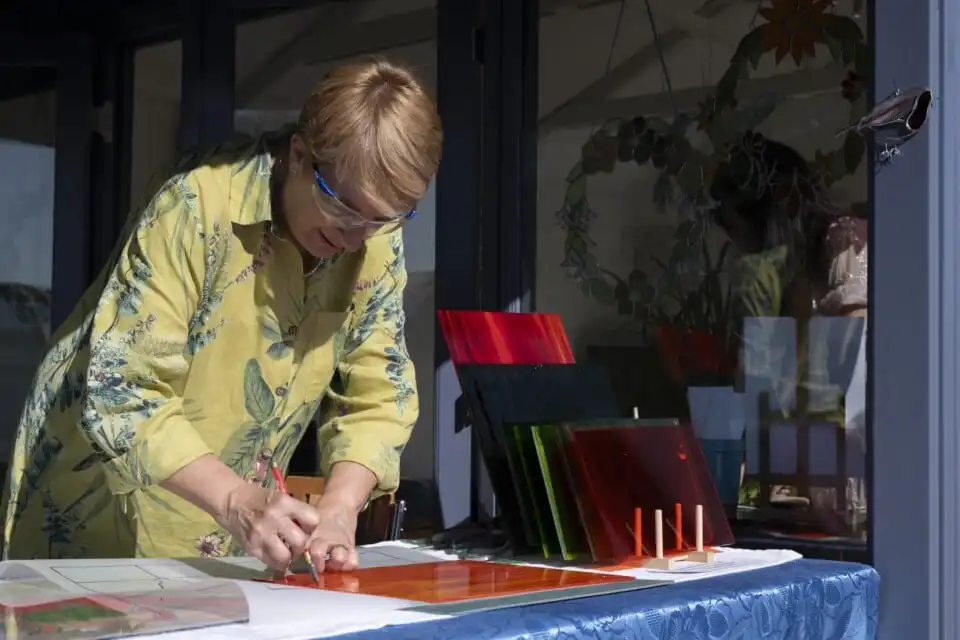 Sarah Davis of Sarah Davis Glass cutting glass pane