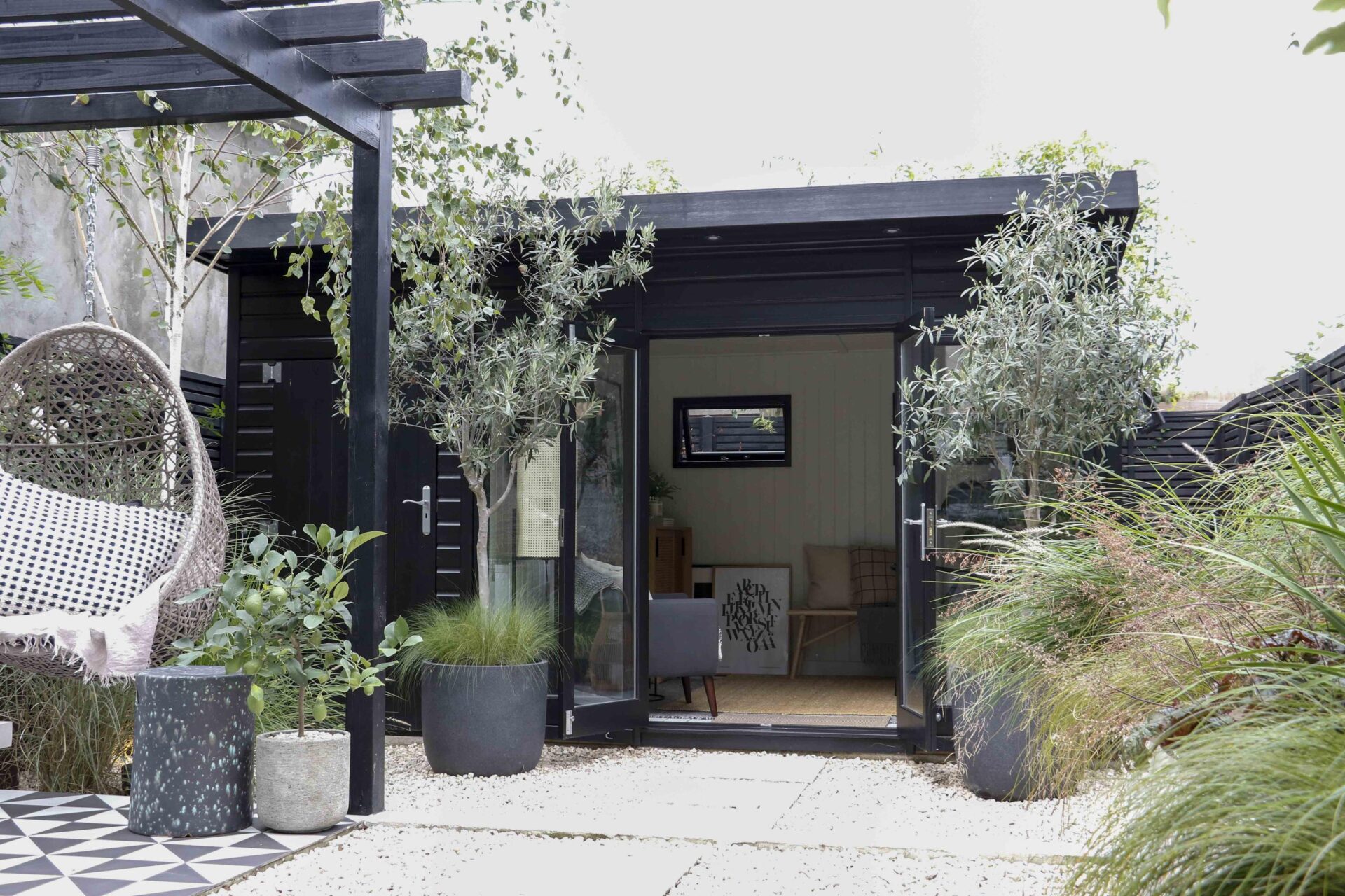 The image depicts a modern, insulated Studio Pent by Malvern Garden Buildings, situated in a typical UK back garden. The building functioned as a home office for our customer.