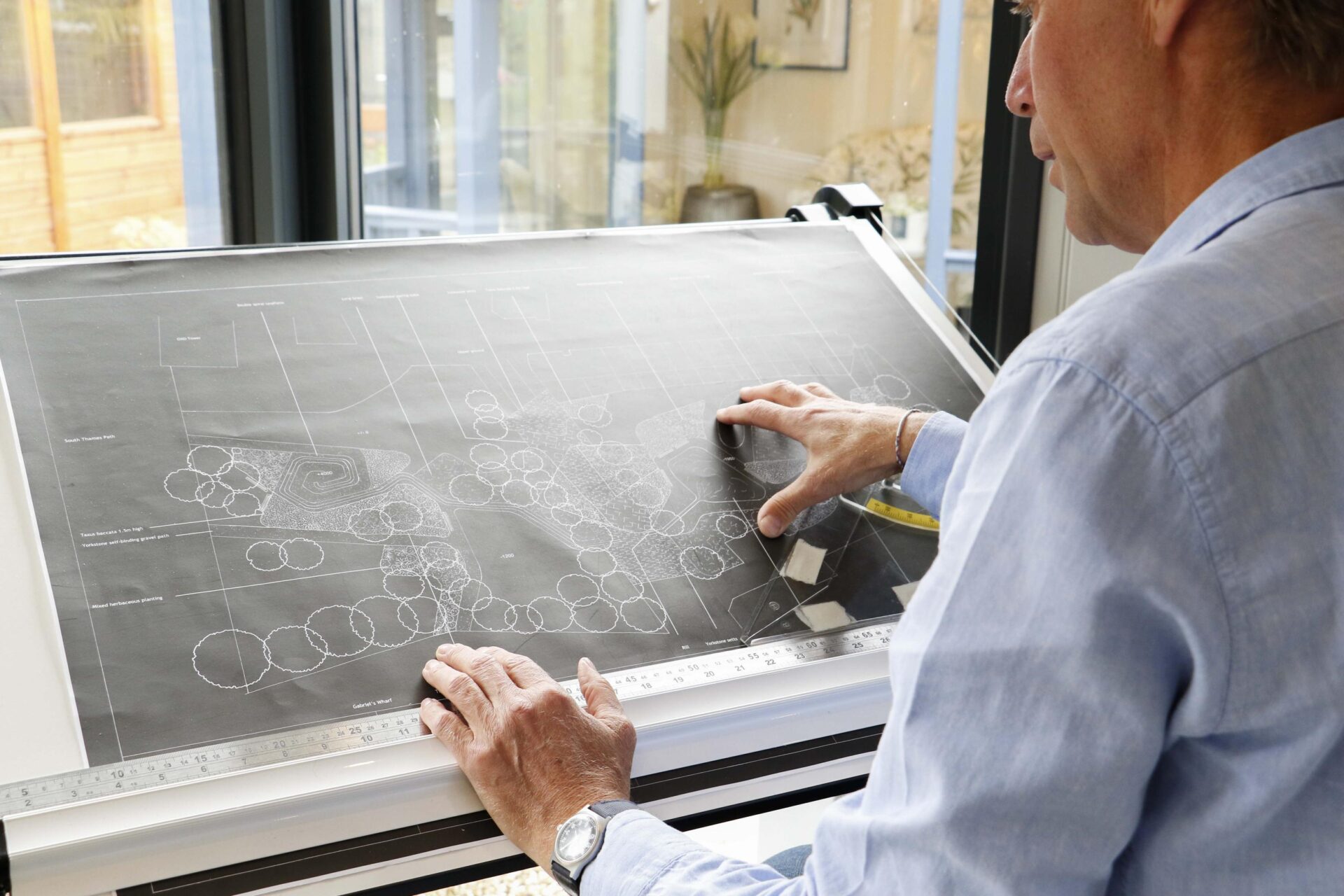 The image depicts our garden room Planning Permission partner looking at technical drawings of a customer's garden.