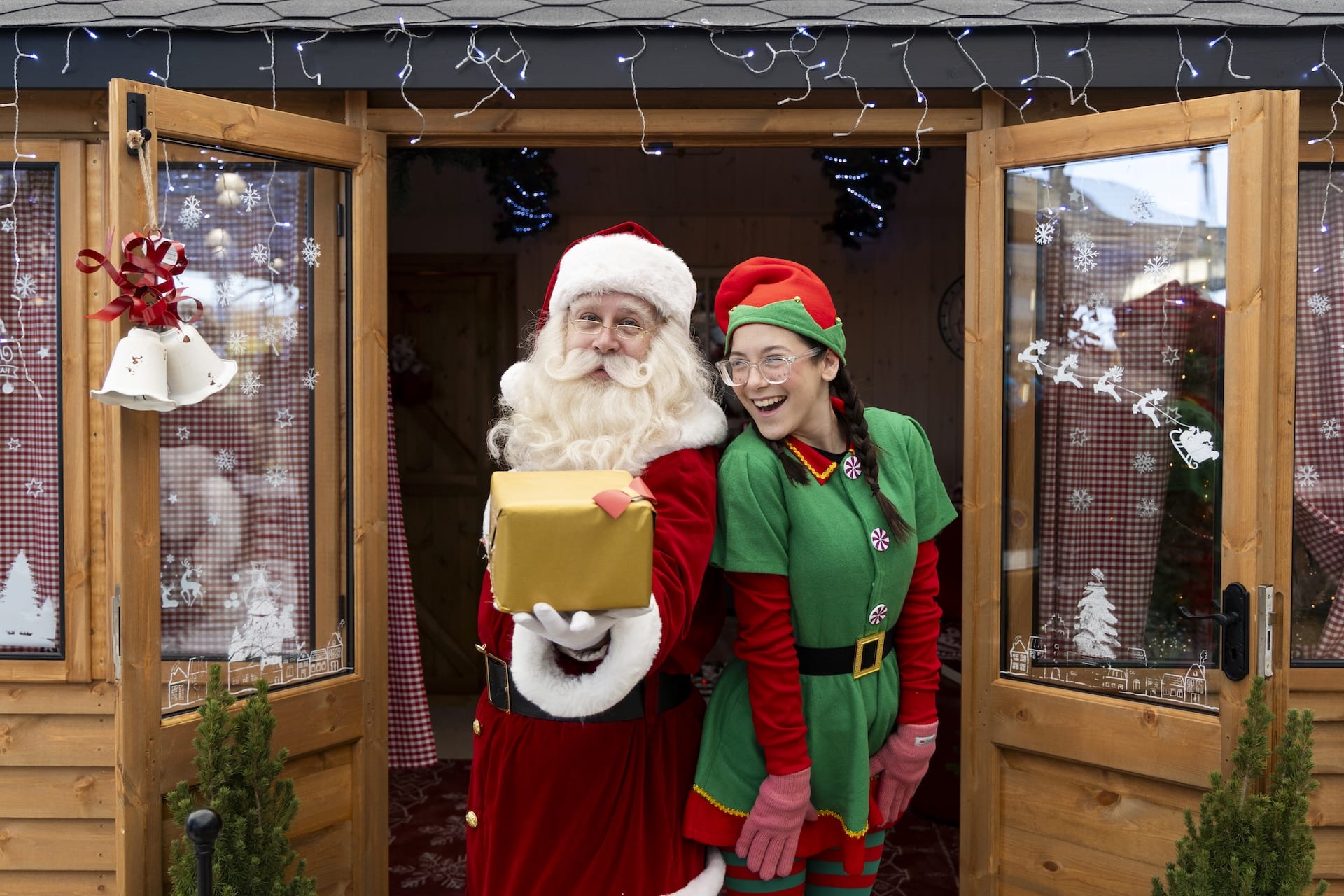 santa and elf holding out wrapped present standing in studio doorway