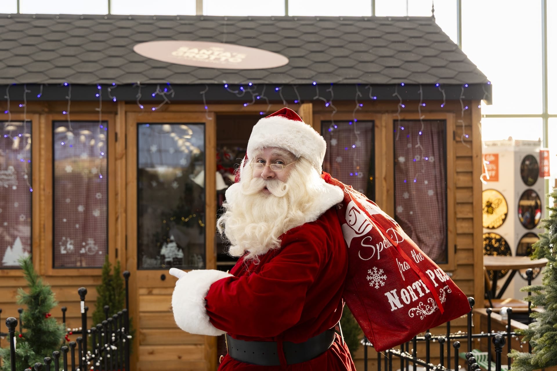 santa holding presents sack pointing at garden building