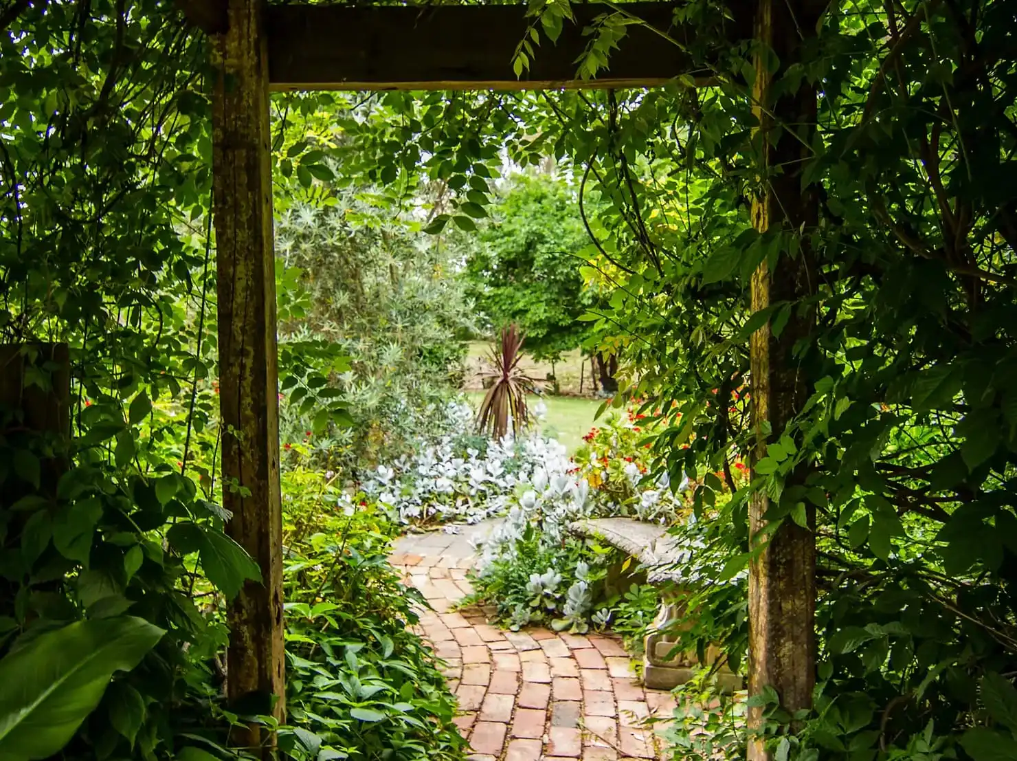 Wabi-Sabi Garden Style. Bricks garden path leads through lush garden archway.